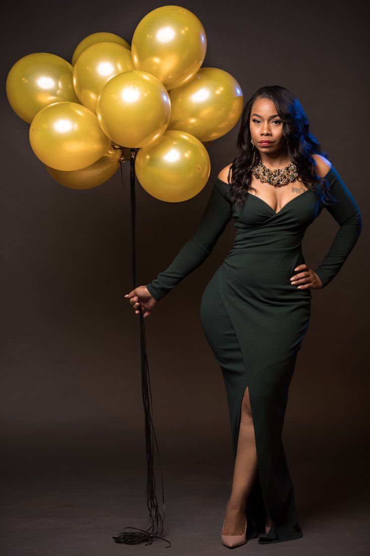 Portrait in an emerald gown holding gold balloons
